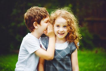 Petit garçon dit secret à petite fille