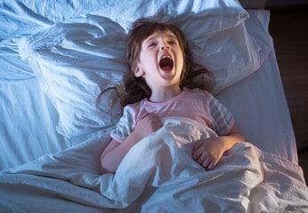 Petit fille qui hurle couchée dans son lit